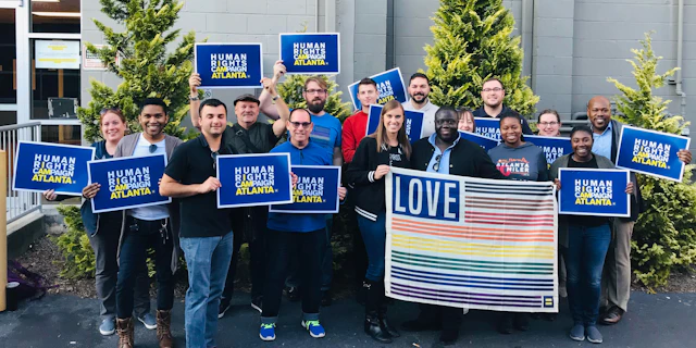 People standing with HRC signs and a large rainbow flag
