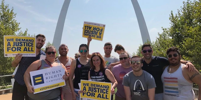 People with signs that say "we demand justice for all" in front of the st louis bend