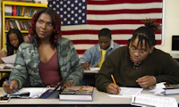 A transfeminine student sitting next to a non-binary student in class