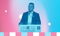 Male presenting person speaking at a podium with a pink white and blue color treatment