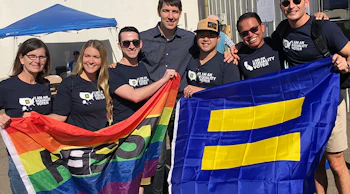 A group of people wearing equality voter t-shirts and carrying an HRC and rainbow flag.