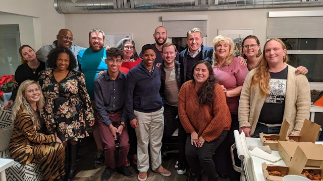 A group of 15 volunteers, of various ages, races and genders poses for a group shot.