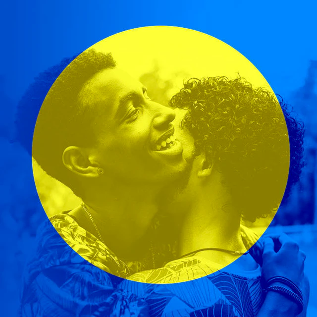 Two young men embrace, smiling.
