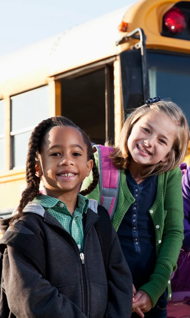 4 kids in front of a school bus